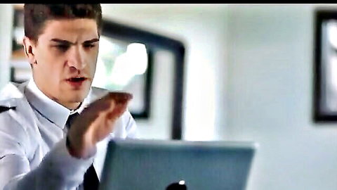 Handsome man in suit gesturing at laptop in office scene