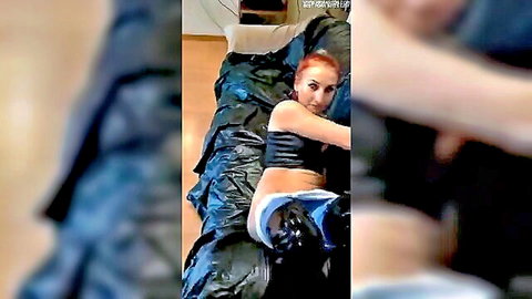 Redhead latex mistress in black top, white panties, and stockings on bed