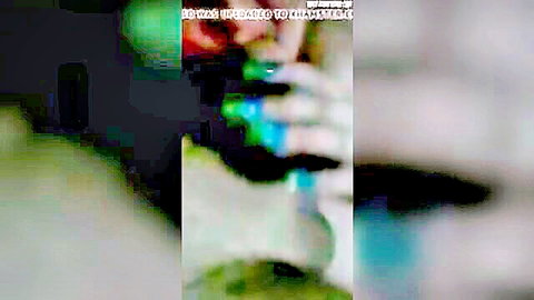 Blurry green-tinted thumbnail of hand holding blue object in blowjob and swallow themed amateur porn
