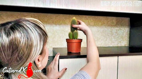 Blonde housewife teasing with phallic cactus plant in casual tease