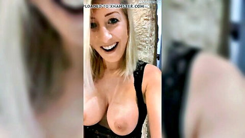 Blonde beauty smiling in revealing black top with exposed nipples against stone wall