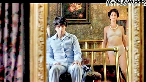 Hot mom in beige lingerie approaches seated son in taboo movie scene