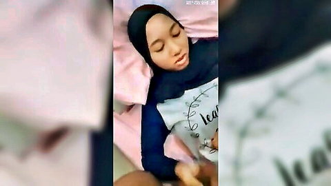 Malaysian hijab girl lying on bed with hand between her spread legs teasing pussy