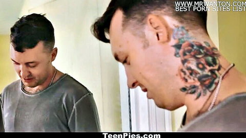 Two young tattooed men in gray shirts standing indoors before TeenPies action