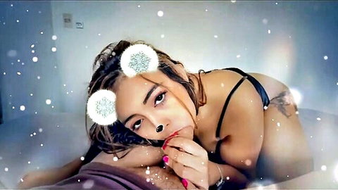 Seductive Latina in black lingerie and bunny ears lounging on bed for Christmas