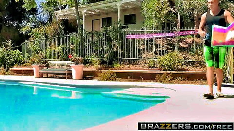 Kiara Mia struts poolside in pink bikini top and green shorts, holding pink surfboard