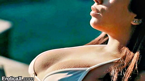 Brunette in white bikini showing deep cleavage poolside tease