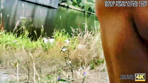 Blurry outdoor scene with tall grass reeds water and tan thigh skin under porn watermarks