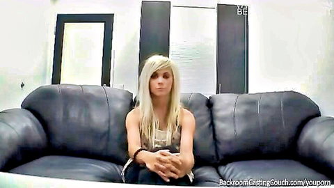 Nervous blonde amateur sits clothed on black leather casting couch