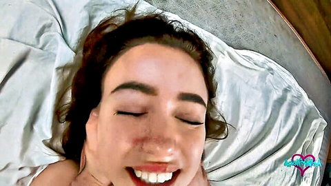 POV closeup of smiling brunette with eyes closed in ecstasy on bed