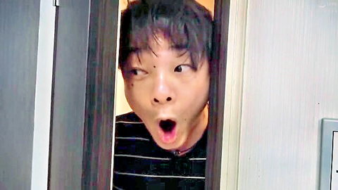 Surprised young Japanese guy peeking through door with wide eyes and open mouth