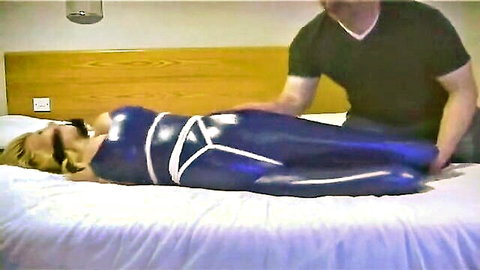 Blonde in tight blue latex catsuit bound with ropes in BDSM scene