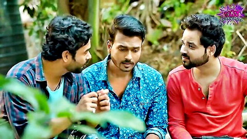 Three South Asian men in colorful shirts sitting closely chatting outdoors in lush green forest.