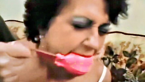 Mature granny in BDSM scene gagging on pink toy, intense throat grip