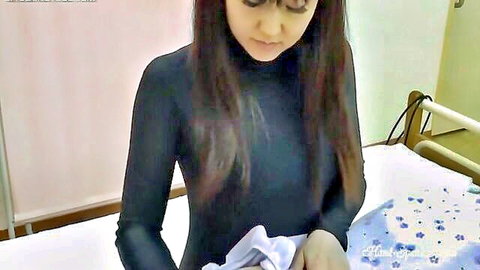 Sexy Asian brunette in tight black turtleneck dress holding white towel by hospital bed