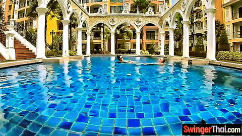Big titted Thai woman floats topless in resort pool with man nearby