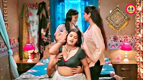 Busty Indian MILF in deep cleavage green blouse and saree exposes big tits and belly as girlfriends caress her on bed