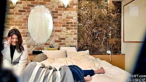 Smiling Asian woman in coat with bound man on bed in BDSM scene