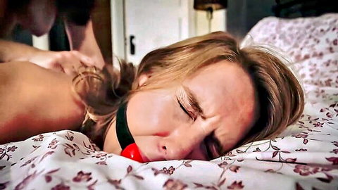 Blonde woman ball-gagged and restrained in intense BDSM stockings scene