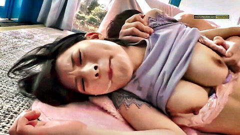 Japanese babe lies on floor with gray shirt pulled up exposing huge bare tits groped by rough hands