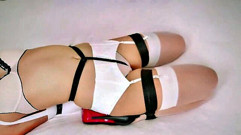 Slim woman in white lingerie and black bondage straps, stockings, red heels, BDSM pose