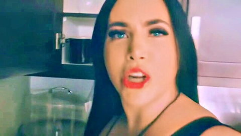 Seductive MILF with long black hair and blue eyes teasing with open mouth in black top
