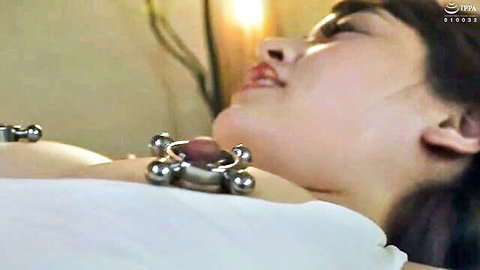 Japanese woman in esthetic room with nipple clamps, ecstatic expression during BDSM therapy