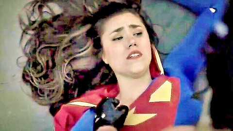Brunette Superwoman in iconic costume, lying with messy hair in adult cosplay scene