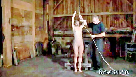 Nude blonde woman bound in ropes by man in BDSM restraint scene