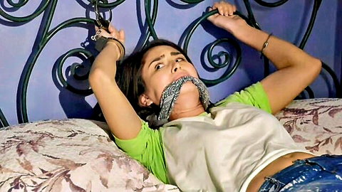 Bound brunette gagged and handcuffed to bed in BDSM domination scene