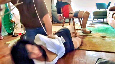 Bound Asian woman in skirt tied on floor by man in BDSM threesome bondage scene