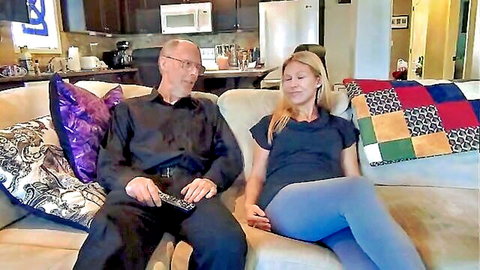 Blonde Ariel lounging with older man on couch in family scene