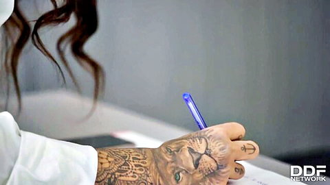 Susy Gala in office, tattooed hand writing with pen