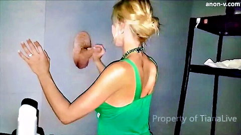 Blonde woman in green top at gloryhole, hands on anonymous cock