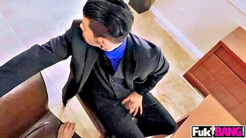 Suited man on couch with hand down pants groping cock as woman's hand teases his crotch