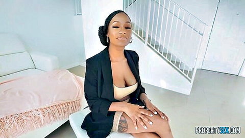 Ebony woman with huge boobs in deep cleavage blazer, smiling seductively