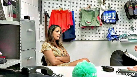 Sofi Ryan in ShopLyfter, arms crossed in floral dress during interrogation