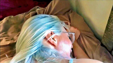 Blue-haired babe with glasses lying relaxed on bed sheets