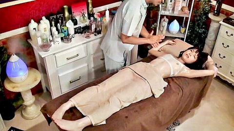 Asian wife topless on massage table, masseur touching her arm