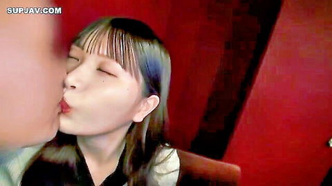 Close-up of man kissing cute Asian girlfriend with bangs in white top