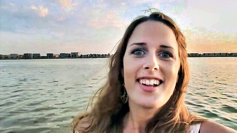 Smiling brunette woman in white top by Dutch waterfront at sunset