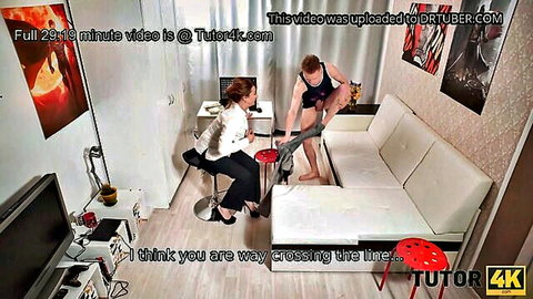 Mature brunette teacher in blouse sits legs crossed as muscular guy in underwear stands close teasing her
