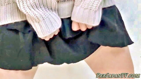Asian woman lifting black skirt in white sweater for pee fetish tease