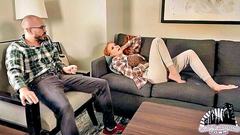 Redhead client lounges on couch as therapist sits nearby in intimate session