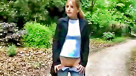 Shy blonde teen pulls down jeans in outdoor casting, exposing midriff