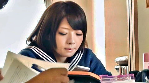 Cute Japanese schoolgirl in sailor uniform studying intently at desk with notebook and pen