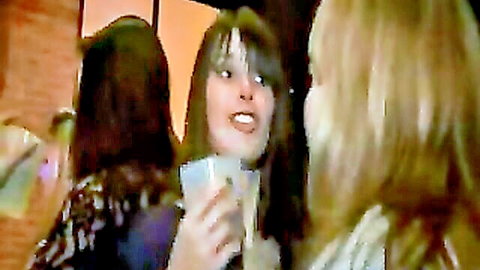 Smiling brunette and blonde women partying with drinks in nightclub group scene