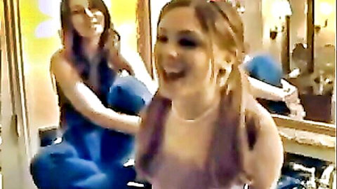 Two playful amateur girls laughing and touching hair in bathroom mirror selfie