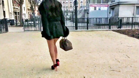 Sexy woman in short black dress and red heels walks outdoors for audition
