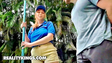 Curvy redhead with big tits in tight blue polo and shorts holds pool pole flirting with guy outdoors